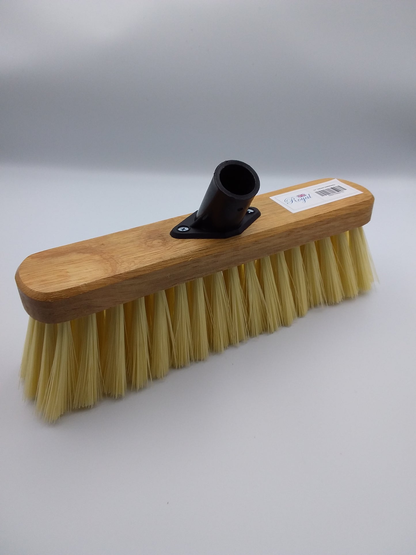 A 11 inch PVC broom head with soft bristles and a wooden block attached for mounting to a handle.