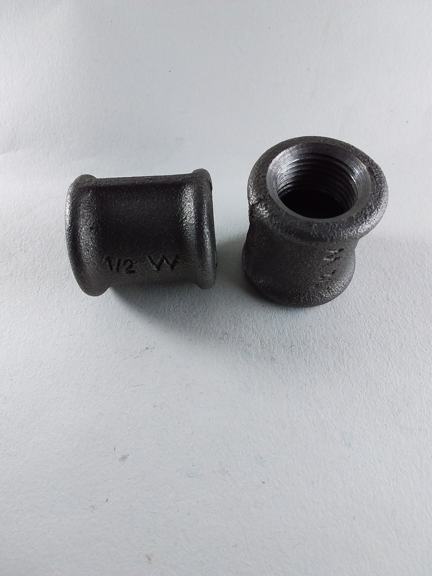 Two black iron sockets, one with threaded end visible, the other showing the interior cylindrical shape.