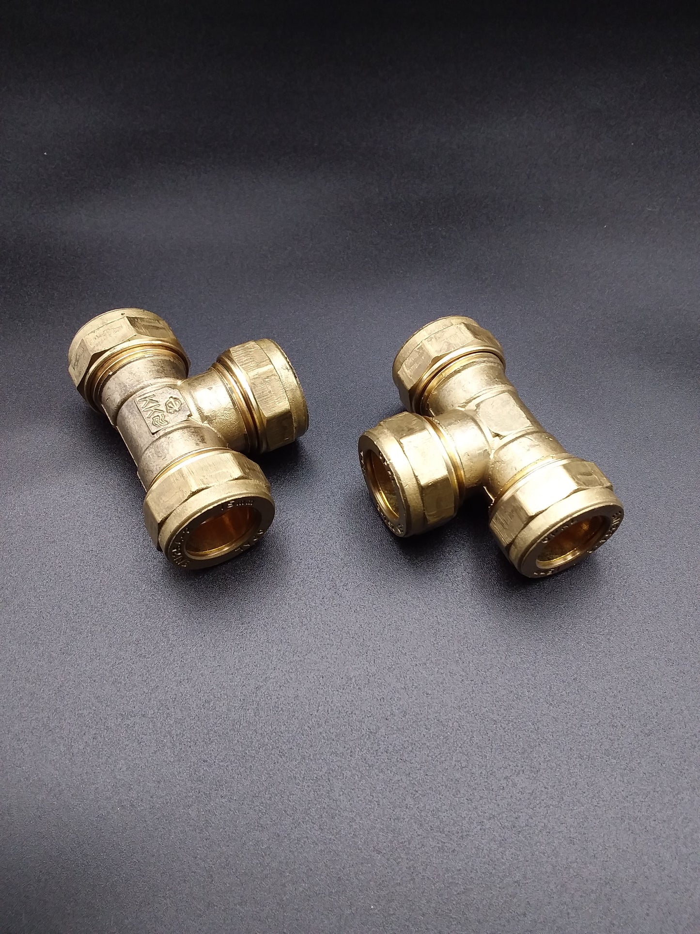 Brass 28mm compression equal tee plumbing fittings on a dark background.