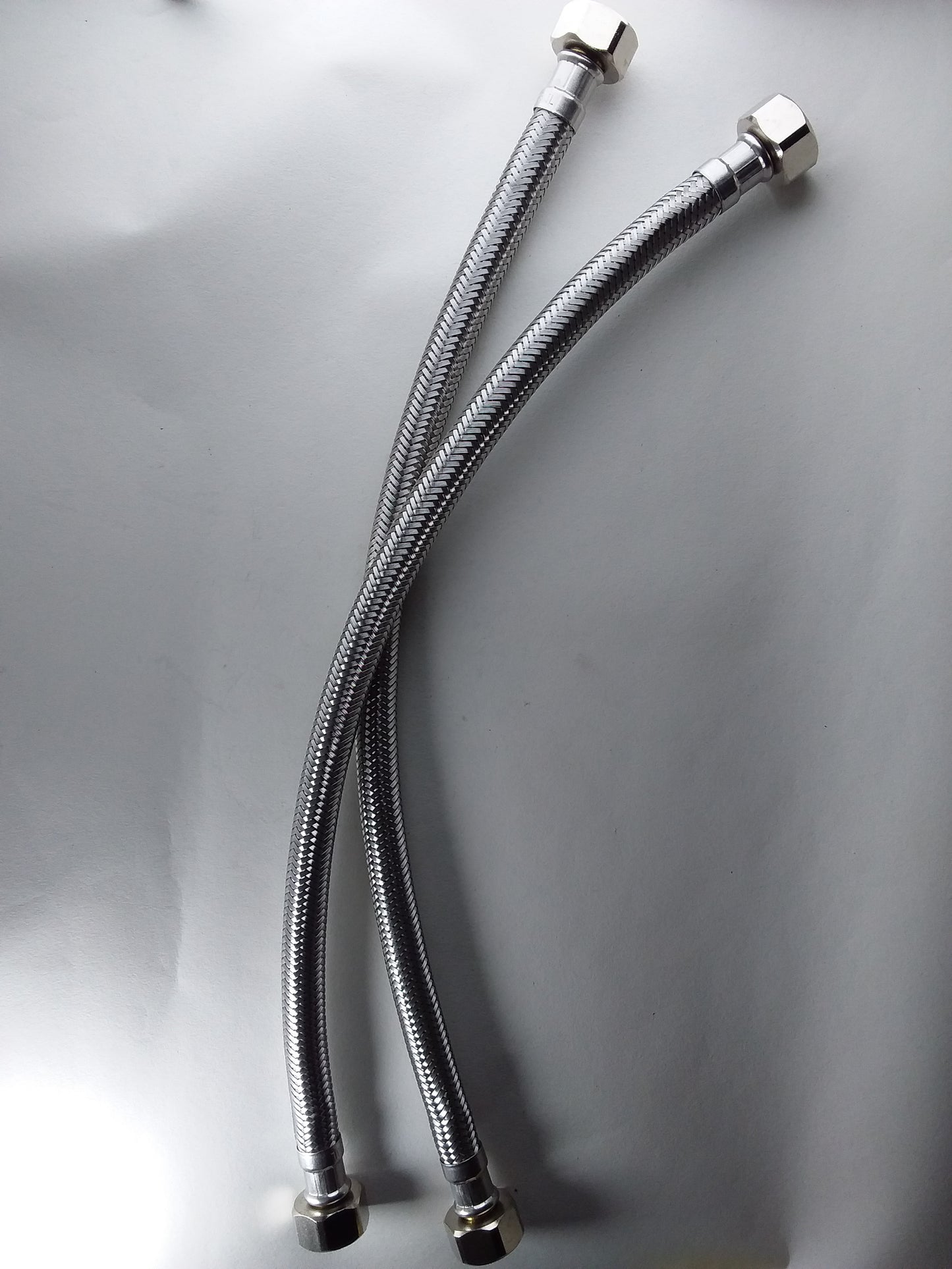 1/2" x 1/2" flexible hoses with metallic finish and connectors at both ends.