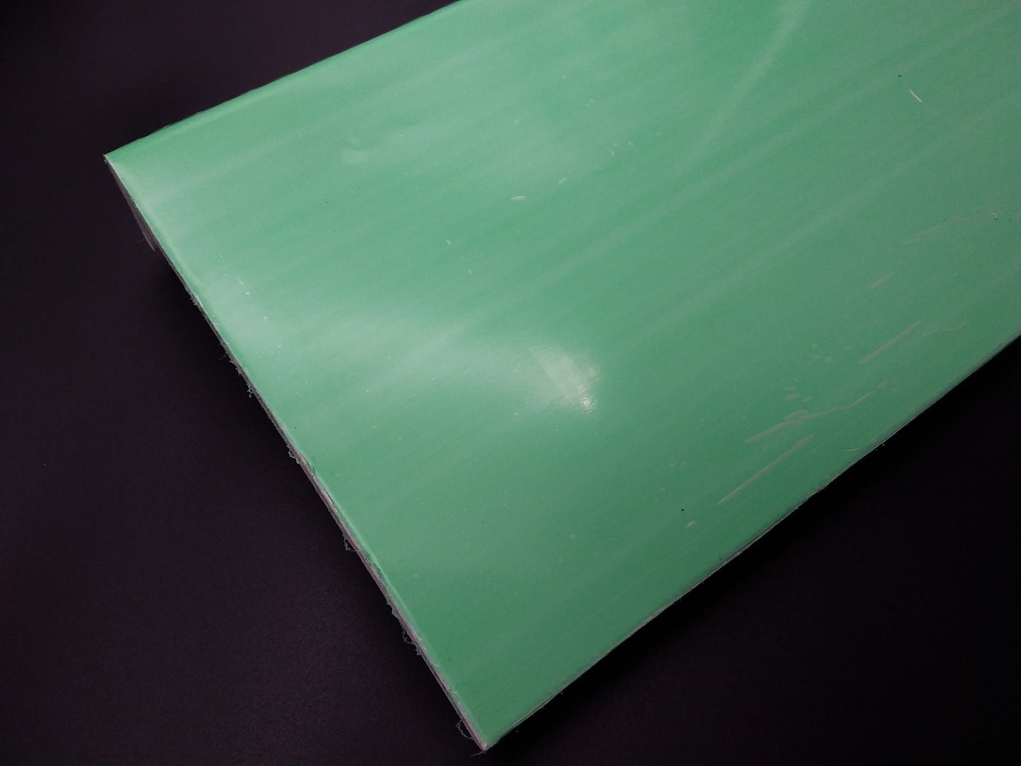 polyester board with a visible green tint, placed against a black background.