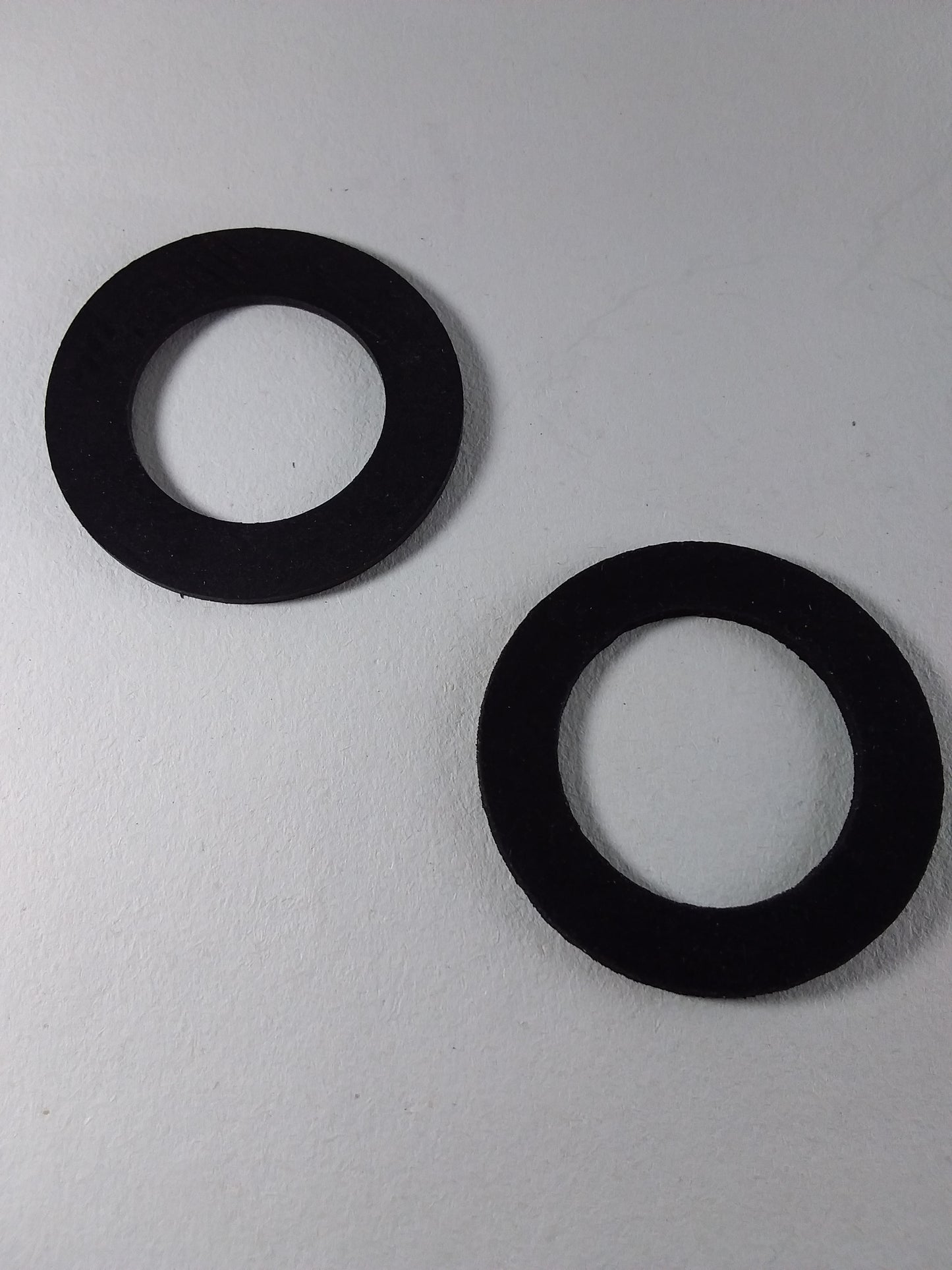 Two black rubber washers for a faucet.