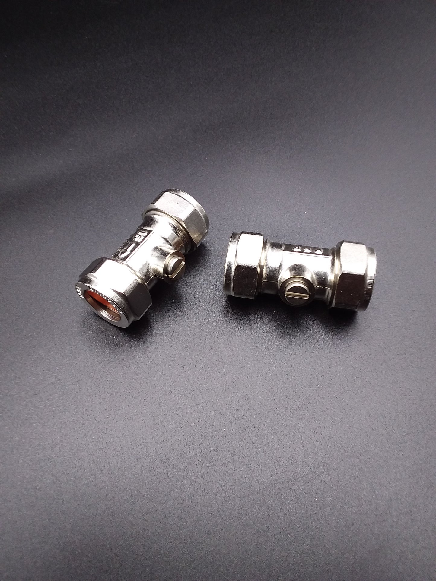 Two 22mm metal isolating valves are shown against a dark background. They are silver in color and have threaded connections for installation.