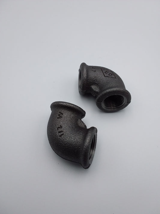 Black iron elbows, plumbing fixtures, placed on a light background.