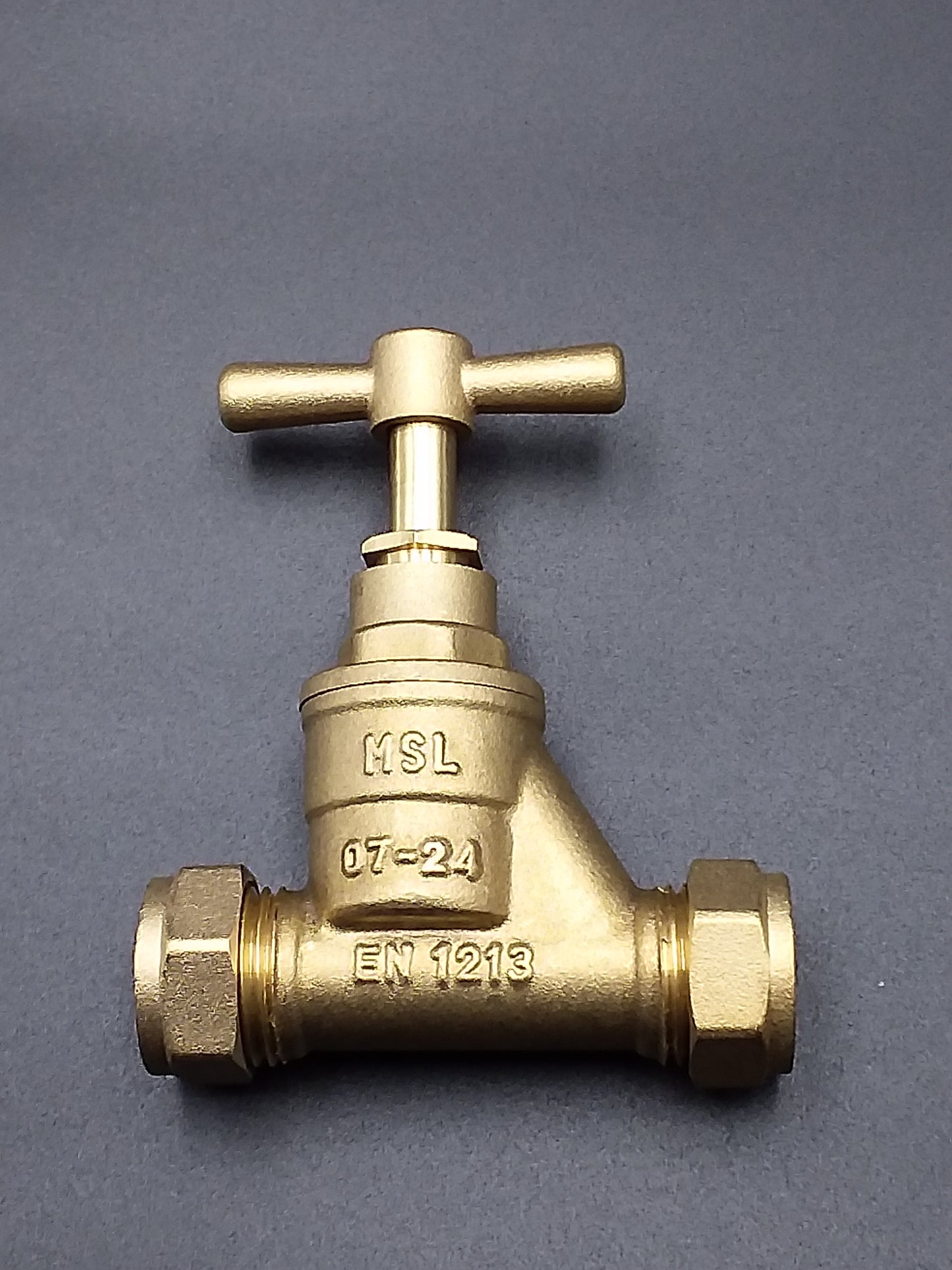 A brass colored 20 x 20mm stop tap with a brass body and a cross handle for turning the tap on and off.