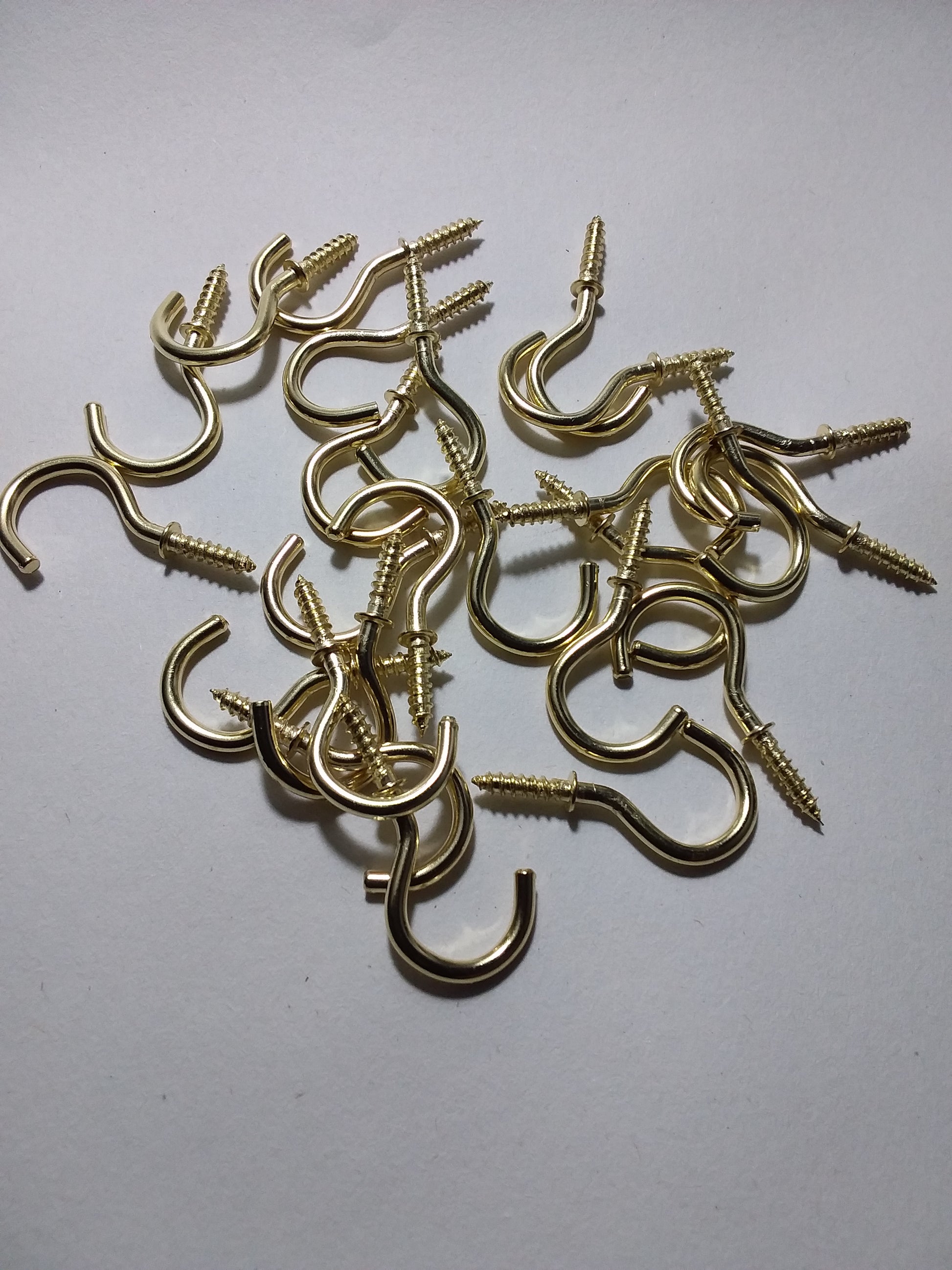 A collection of small brass cup hooks with screw portions, displayed on a white background.