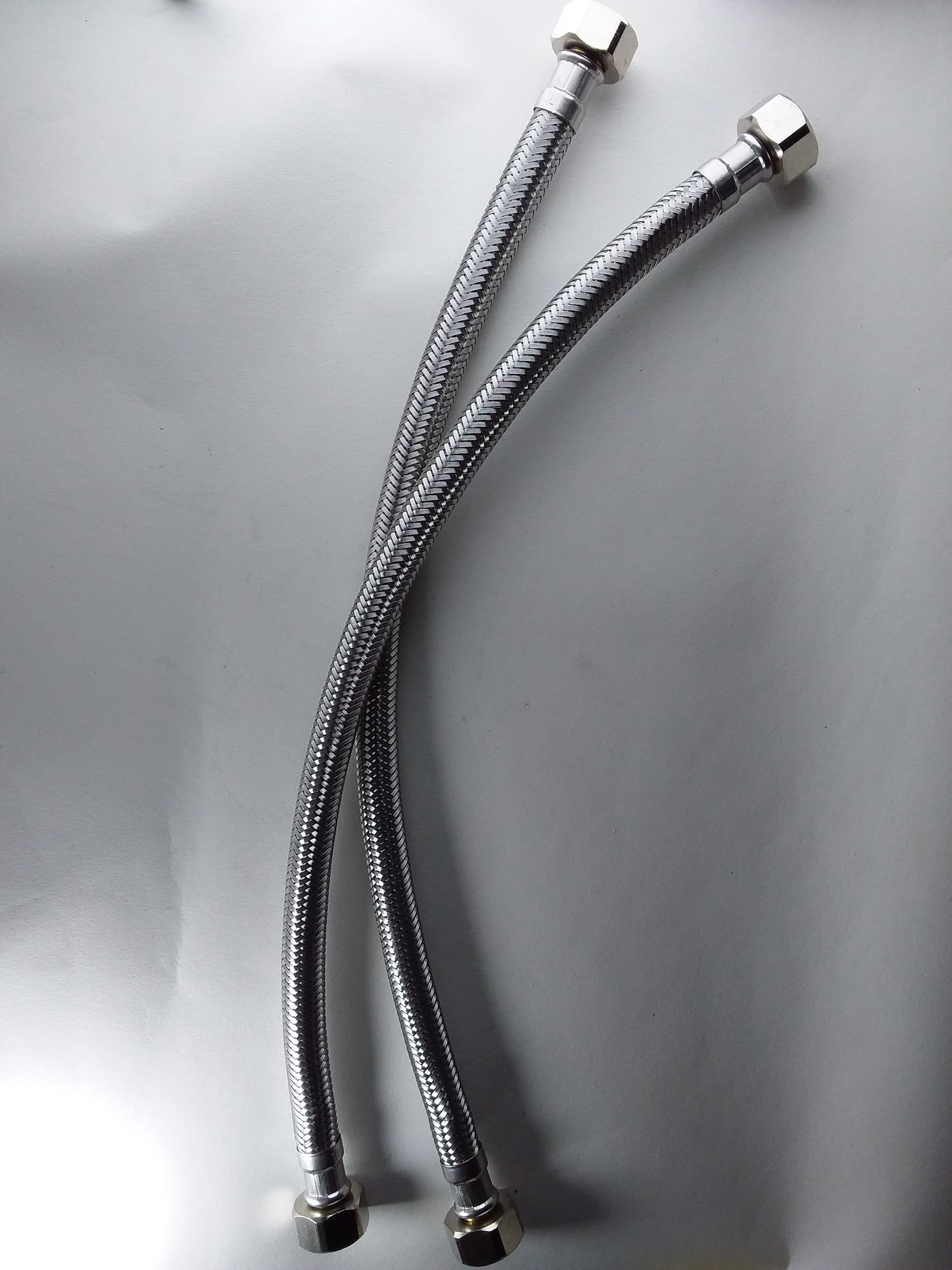 1/2" x 1/2" flexible hoses with metallic finish and connectors at both ends.