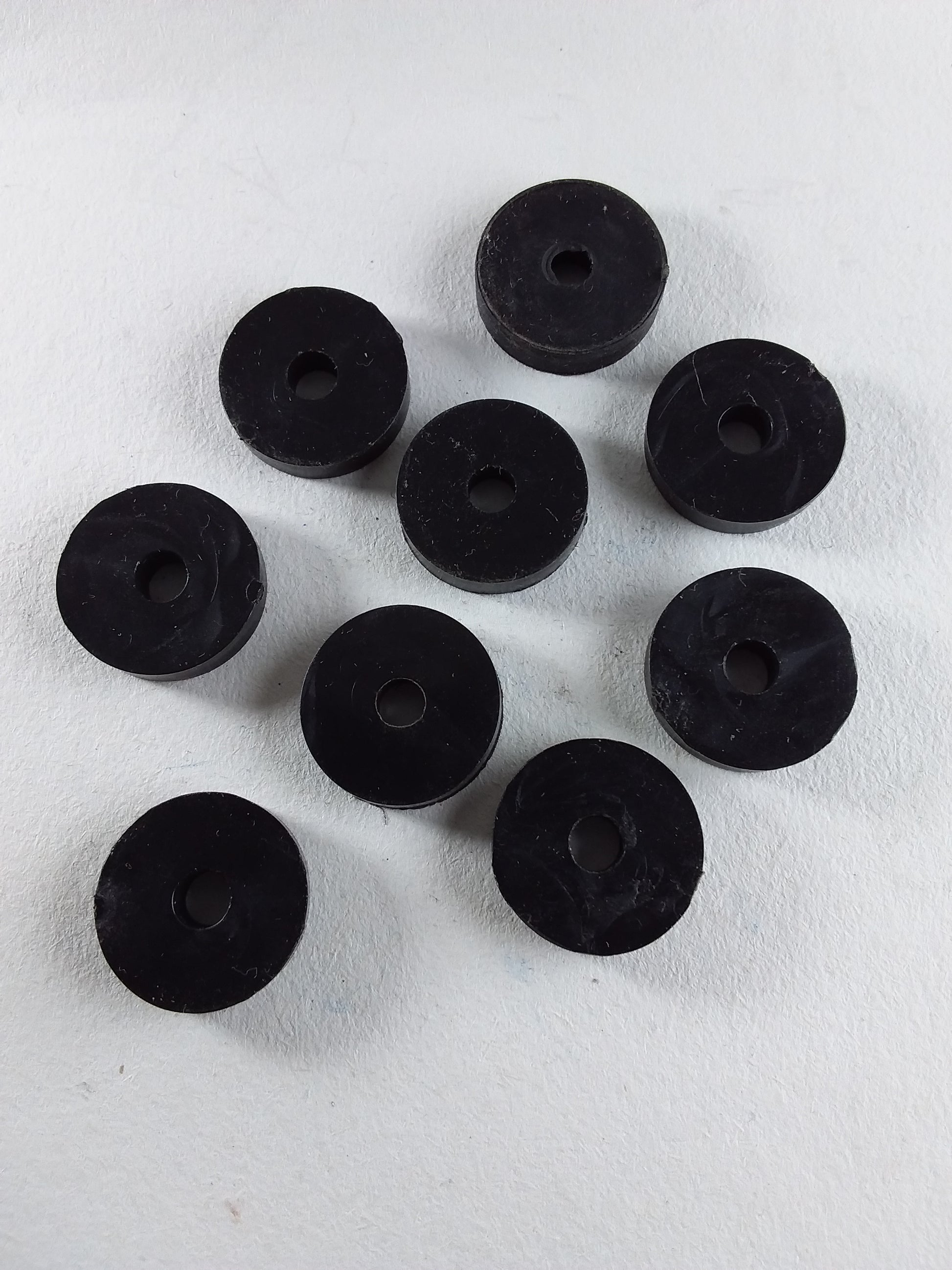 A collection of black flat tap washers arranged on a white surface.