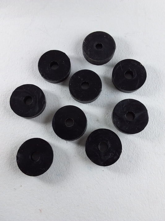 A collection of black flat tap washers arranged on a white surface.