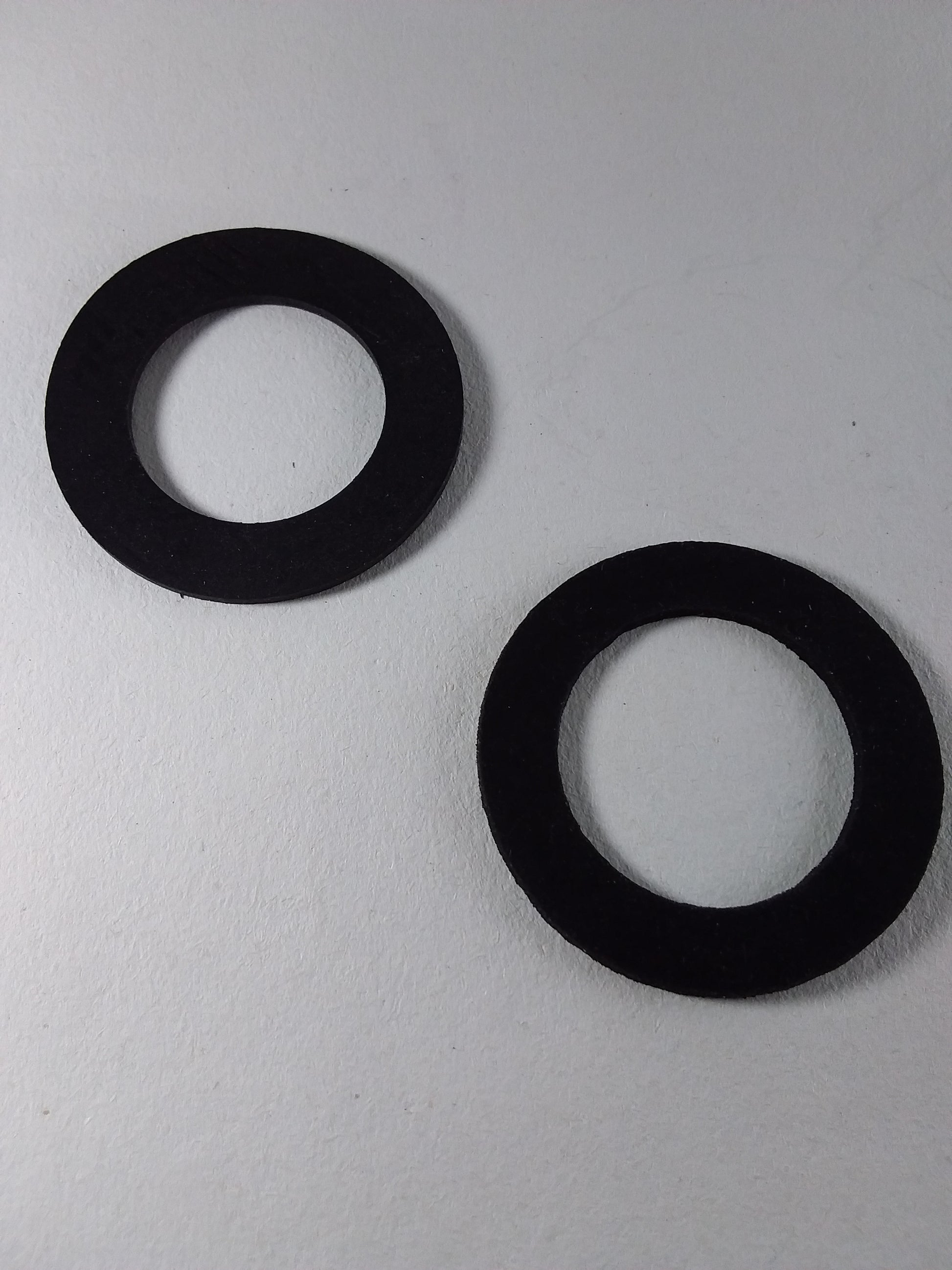 Two black rubber washers for a faucet.